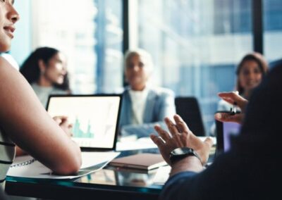 Industry professionals discussing pharmaceutical logistics strategy during a boardroom meeting with data presentation on screen.